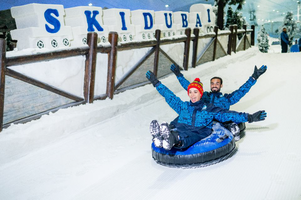 A couple of people riding a snow tube  Description automatically generated