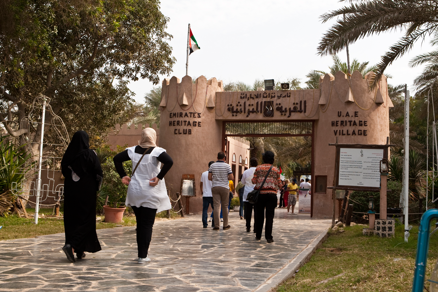 A group of people walking in front of a gate  Description automatically generated